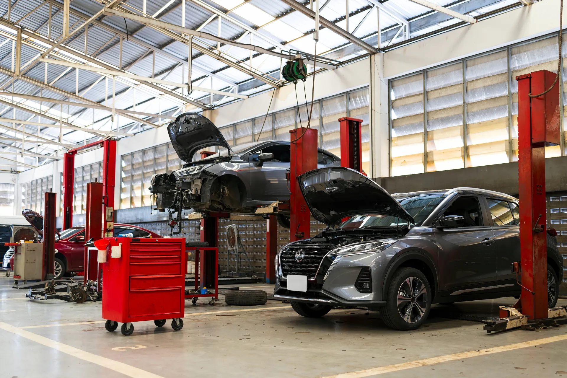 Atelier du garage automobile à Sartrouville : véhicules sur ponts élévateurs, capot ouvert