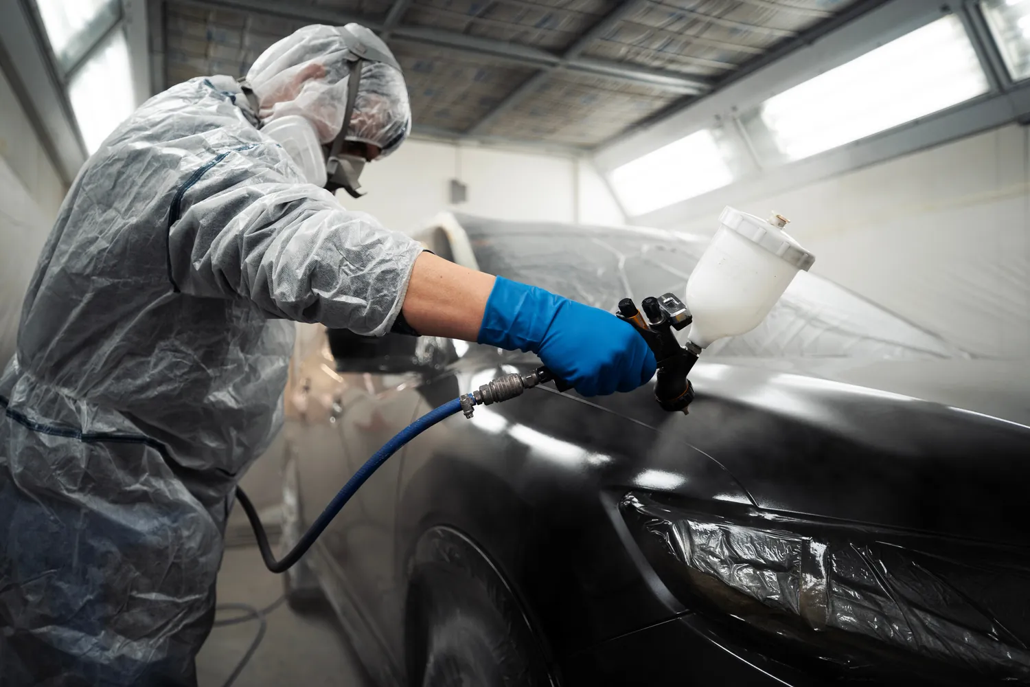 Carrossier peintre au pistolet dans la cabine de peinture
